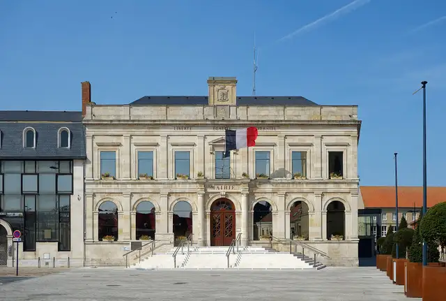 The stone town hall of Gravelines with a French flag over the door.